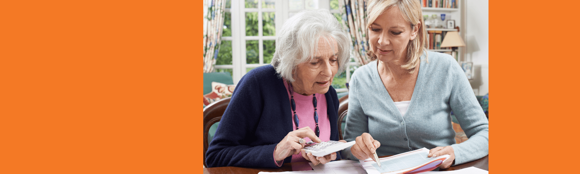 Senior female uses calculator and another female shows information on paper