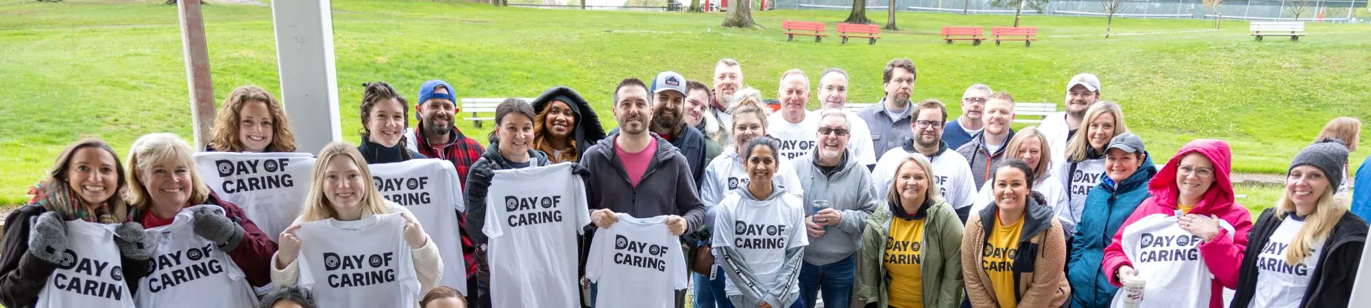 Day of Caring volunteers hold up their Day of Caring shirts