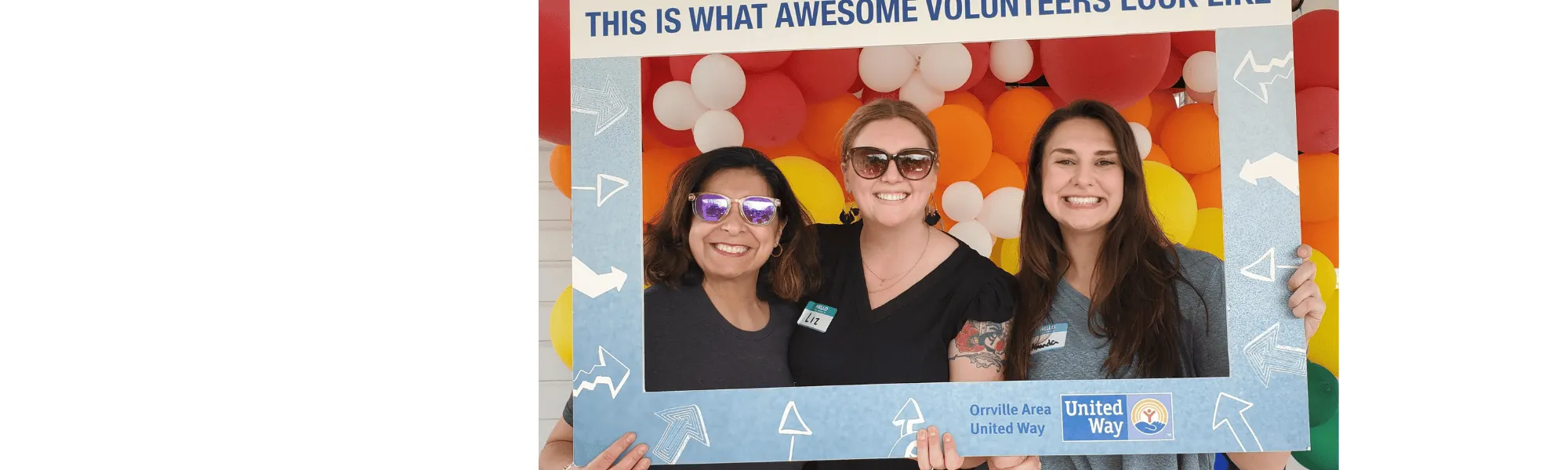 Three volunteers standing together and smiling while holding an appreciation sign